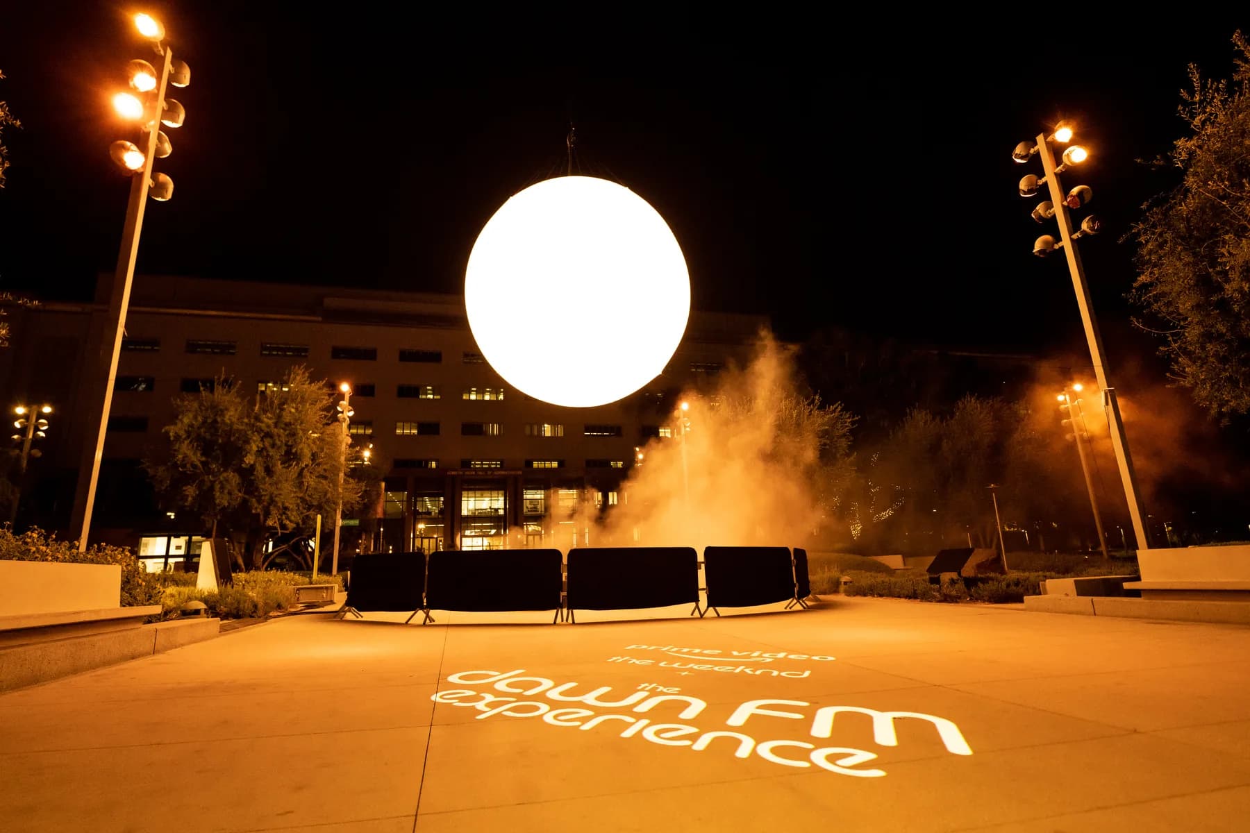 Dawn FM orb installation projected with orange light outdoors at night